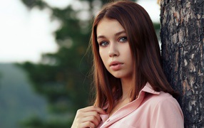 Нежная девушка стоит у дерева
