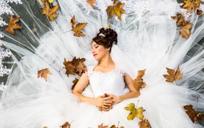 Девушка невеста в белом платье лежит с желтыми листьями
