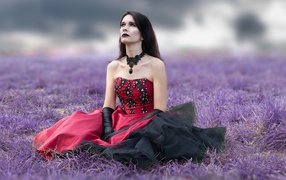 Девушка с макияжем в красивом платье сидит на траве
