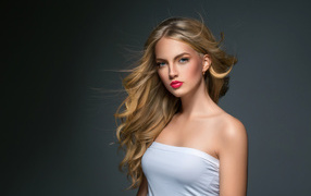 Young beautiful blue-eyed blonde on a gray background