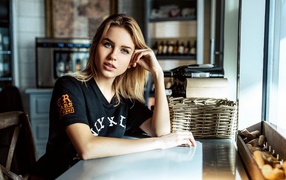 Молодая голубоглазая девушка сидит в кафе