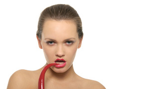 Молодая девушка кусает красный перец на белом фоне