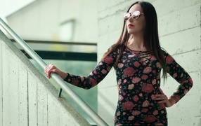 Молодая девушка в солнечных очках стоит на ступеньках