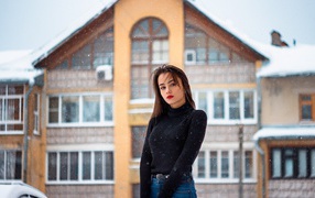 Молодая девушка на фоне заснеженного дома зимой