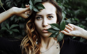Молодая девушка с зелеными листьями в руках 