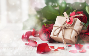 Подарок в коробке на столе с красными розами