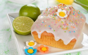 Красивый пасхальный кулич на белой тарелке с лаймом и сахарными цветами