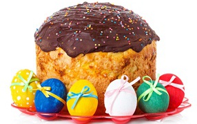 Большой пасхальный кулич с шоколадной глазурью на белом фоне с крашеными яйцами 