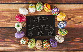 Надпись на английском Счастливой Пасхи на столе с крашеными яйцами