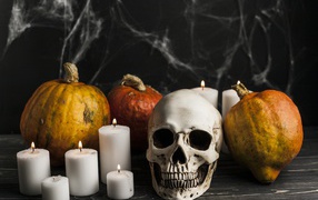 Skull, candles and pumpkins on the table with cobwebs