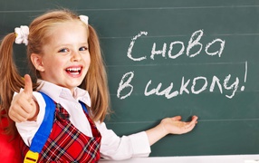 Smiling little schoolgirl on Knowledge Day on September 1 at the blackboard