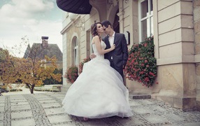 Жених и невеста стоят у здания 