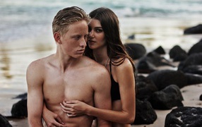 Влюбленная пара сидит на камнях на берегу моря 