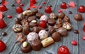 Сладкое сердце из шоколадных конфет на деревянном столе