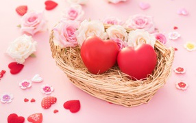 Два красных сердца лежат в корзинке с розами 