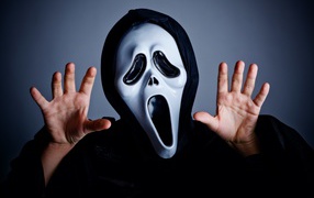 Мужчина в маске пугает на сером фоне