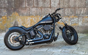 Черный стильный мотоцикл Harley-Davidson на фоне стены