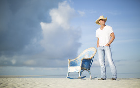 Кантри исполнитель Кенни Чесни в креслом на пляже