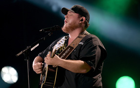 Кантри исполнитель Люк Комбс с гитарой поет на сцене