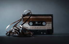 Старая кассета с вытянутой пленкой на сером фоне 