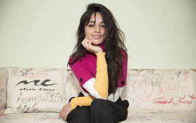 Улыбающаяся Камила Кабельо сидит на диване