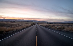 Асфальтная дорога уходит вдаль на фоне неба