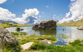 Большой камень в воде на фоне голубого неба