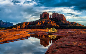 Скалы под пасмурным небом отражаются в воде