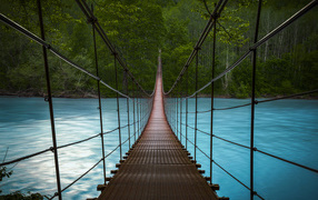 Подвесной мост над быстрой рекой с голубой водой