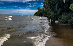Морские волны омывают берег под голубым небом 