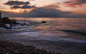 Мелкие камни на берегу моря на закате