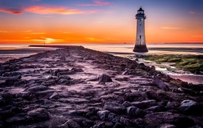 Каменная дорога ведет к маяку у моря