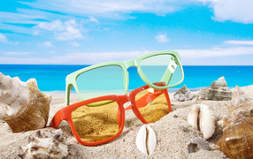 Очки на песке с ракушками у моря летом
