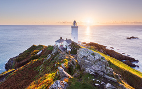Lighthouse on the edge of a cliff in the rays of the bright summer sun