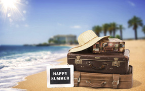 Suitcases and hat on white sand in the sunshine in summer