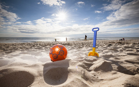 Toys on white sand in the rays of the bright summer sun