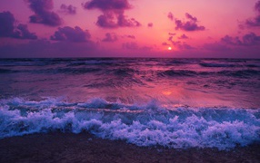 Raging waves on the shore against a purple sunset