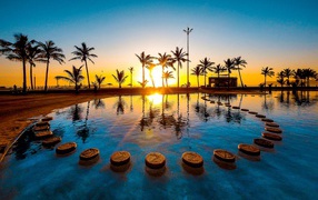Sunset on a tropical beach against the backdrop of the pool