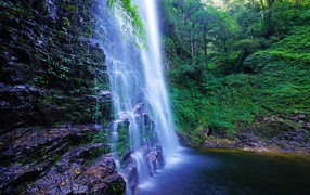 Быстрый водопад стекает по мокрым камням со скалы