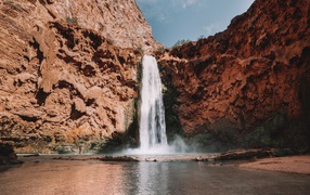 Водопад стекает со скалы в озеро 