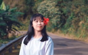 Девушка азиатка с красным цветком гибискуса в волосах