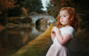 Красивая рыжеволосая девочка у реки в парке 
