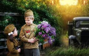 Маленький мальчик с девочкой в военной форме с букетом сирени на 9 мая 