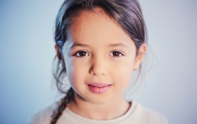 Маленькая кареглазая девочка на сером фоне