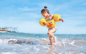 Little cheerful girl runs on the sea water