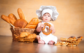 Маленький поваренок на столе со свежей выпечкой