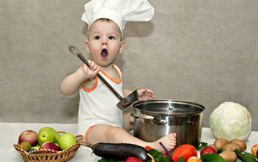 Маленький поваренок с кастрюлей на столе с овощами