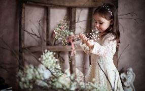 Little girl in a beautiful dress with white flowers in her hand