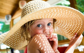 Little girl in a big straw hat in the summer