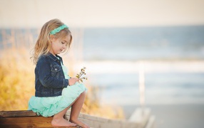 Маленькая девочка сидит на мосту